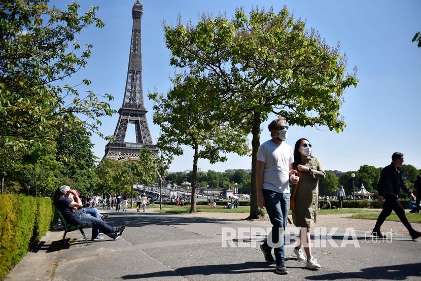 Muslim Amerika Diperingatkan tidak Pergi ke Prancis. Sejumlah orang mengenakan masker menikmati sinar matahari di depan Menara Eiffel pada akhir pekan pertama setelah dua bulan diberlakukannya lockdown di Paris, Prancis,Ahad (17/5). Prancis mulai melongarkan lockdown secara bertahap di tengah pandemi COVID-19. 