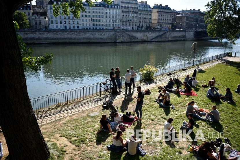 Sejumlah orang menikmati sinar matahari di sepanjang tepi sungai Seine pada akhir pekan pertama setelah dua bulan diberlakukannya lockdown di Paris, Prancis,Ahad (17/5/2020). ilustrasi