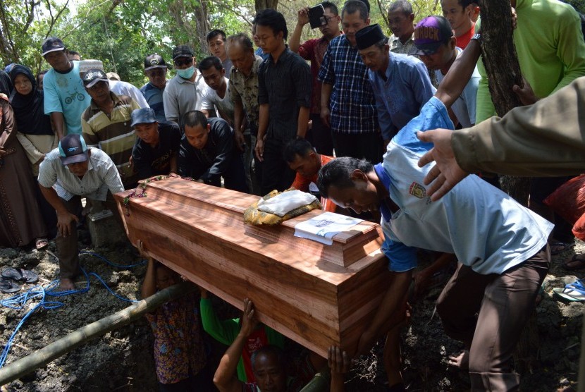 Sejumlah orang menurunkan peti jenazah korban kebakaran Gunung Lawu di pemakaman umum Desa Brangol, Kecamatan Karangjati, Kabupaten Ngawi, Jawa Timur, Selasa (20/10).
