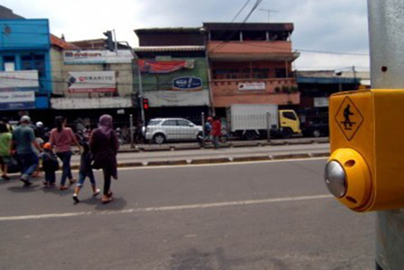 Sejumlah orang menyeberang jalan dengan menggunakan tombol penyeberangan dilampu merah kawasan Pasar Jatinegara, Jakarta Timur, Senin (6/2).(Republika/Prayogi)