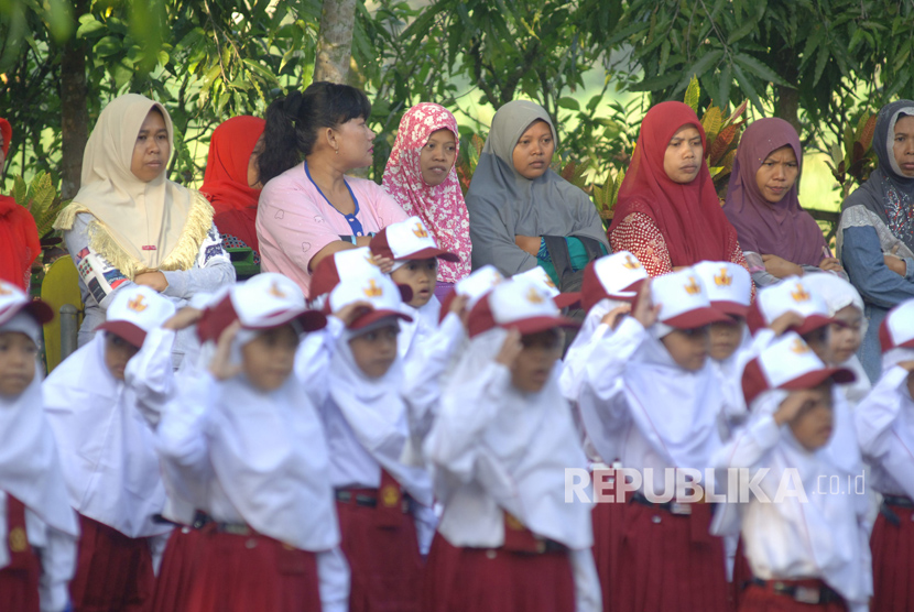 Sejumlah orang tua mendampingi anaknya yang mengikuti upacara bendera di SDN Kowel 3, Pamekasan, Jawa Timur, Senin (17/7).