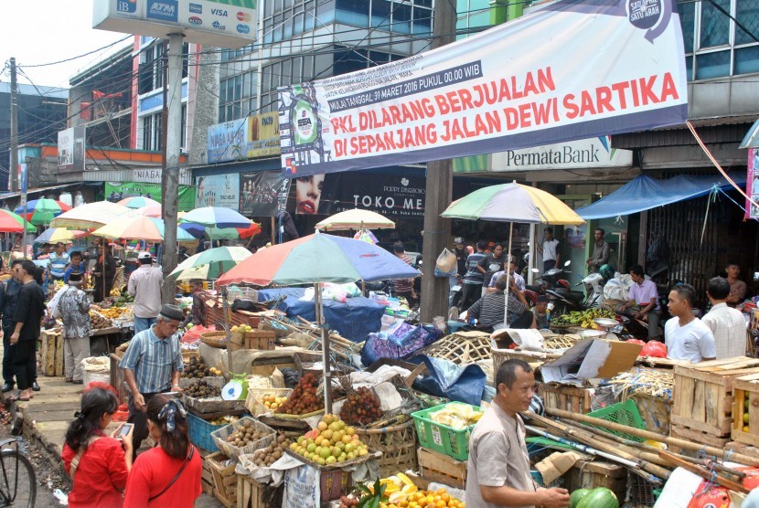 Sejumlah pedagang kaki lima (PKL) menjual barang dagangannya di bawah spanduk larangan berjualan untuk PKL di jalan Dewi Sartika, Kota Bogor, Jawa Barat