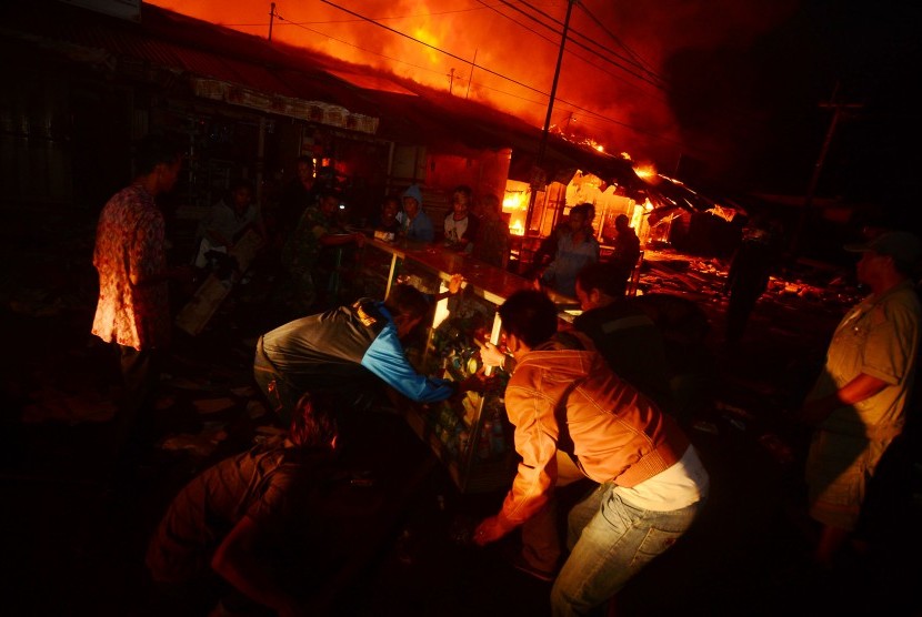 Sejumlah pedagang menyelamatkan barang dagangan dari kios yang terbakar di Pasar Tradisional 