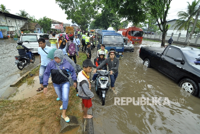   Sejumlah pejalan kaki dan kedaraan berusaha melintasi banjir di kawasan Jalan Raya Rancaekek di depan Pabrik PT Kahatek, Kabupaten Bandung, Jawa Barat, Selasa (1/11).(Republika/Mahmud Muhyidin)