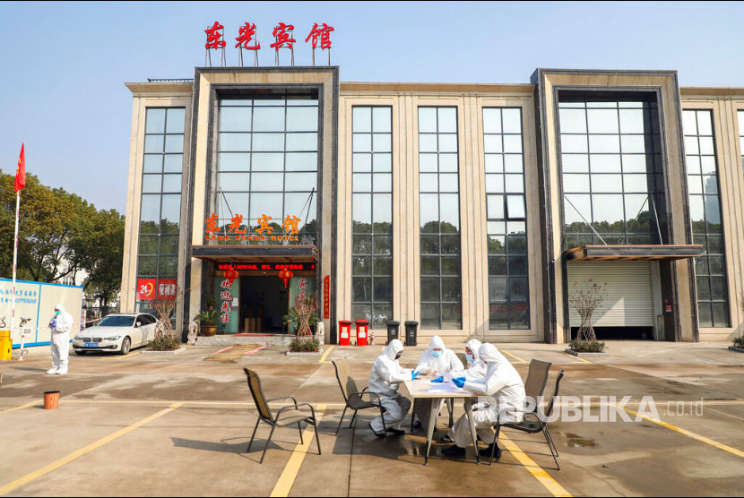 Kematian Virus Corona Lampaui 1.600 Jiwa. Sejumlah pekerja dengan pakaian pelindung menunggu di luar hotel yang digunakan sebagai tempat isolasi warga di Wuhan, Hubei, China. 