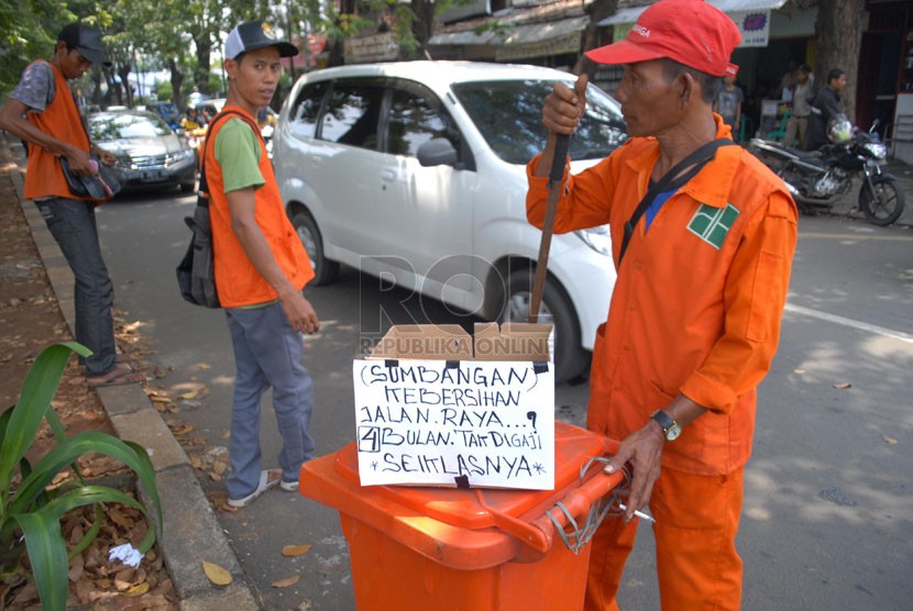   Sejumlah pekerja harian lepas (PHL) Dinas kebersihan DKI Jakarta meminta sumbangan kepada para pengendara yang melintas di kawasan Rawamangun, Jakarta Timur, Kamis (17/4). (Republika/Rakhmawaty La'lang)
