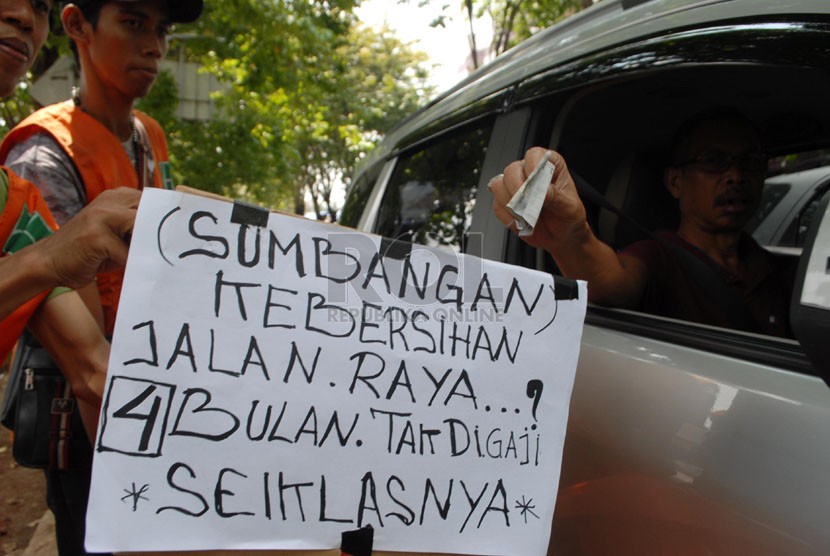   Sejumlah pekerja harian lepas (PHL) Dinas kebersihan DKI Jakarta meminta sumbangan kepada para pengendara yang melintas di kawasan Rawamangun, Jakarta Timur, Kamis (17/4). (Republika/Rakhmawaty La'lang)
