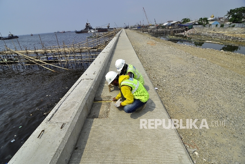  Sejumlah pekerja melakukan pengukuran saat penyalesaian pembangunan proyek tanggul National Capital Integrated Coastal Development (NCICD) tahap 2 paket 2 di kawasan Kalibaru-Cilincing, Jakarta Utara, Selasa (1/8). 