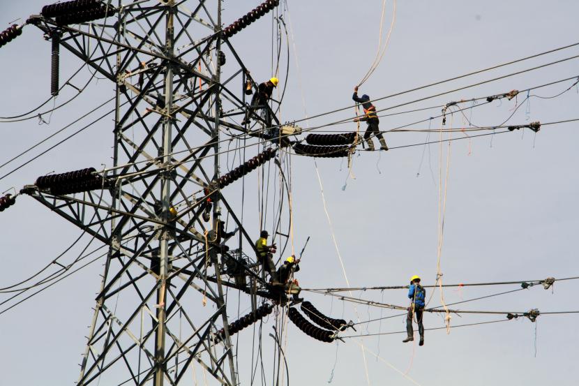 Sejumlah pekerja memasang jaringan transmisi tenaga listrik. PT PLN (Persero) sukses menjaga keandalan pasokan listrik selama pertemuan delegasi G20 di Pulau Lombok. Ilustrasi.