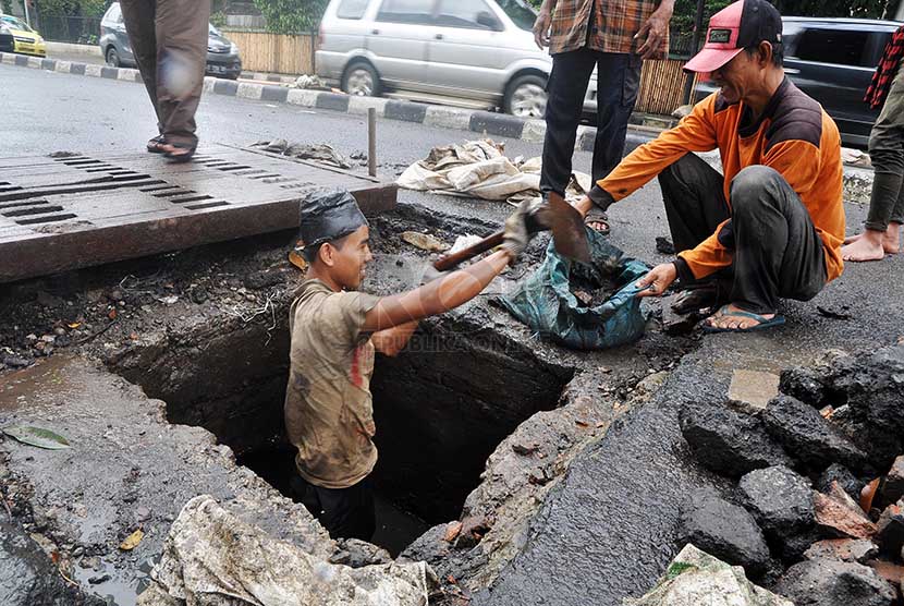 Sejumlah pekerja membersihkan endapan sampah di saluran air Jalan H.O.S Cokroaminoto, Jakarta Pusat, Senin (24/2).