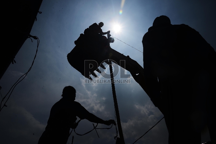 Sejumlah pekerja memperbaiki kabel listrik dengan menggunakan eskavator di Kawasan Pluit, Jakarta Utara, Selasa (20/1). (Republika/Raisan Al Farisi)