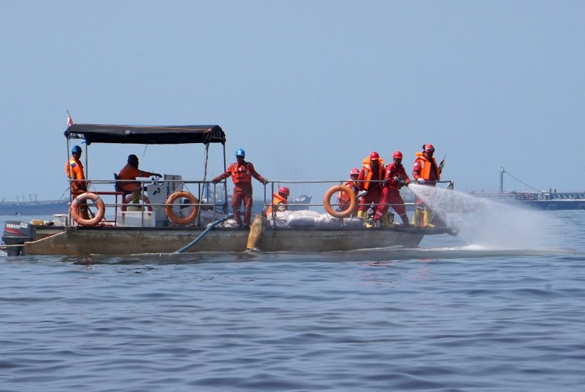 Sejumlah pekerja menaburkan senyawa oil dispersant yang digunakan untuk membersihkan sisa tumpahan minyak mentah yang terkumpul di tepian pantai Teluk Penyu, Cilacap, Jateng, Selasa (26/5).(Antara/Idhad Zakaria)