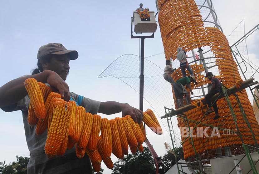 Sejumlah pekerja menata jagung saat proses pendirian menara jagung di Komplek Perkantoran Terpadu Kabupaten Boyolali, Jawa Tengah, Jumat (21/10). Menara setinggi 15 meter yang membutuhkan sebanyak 18.000 bonggol jagung tersebut akan digunakan sebagai ikon 