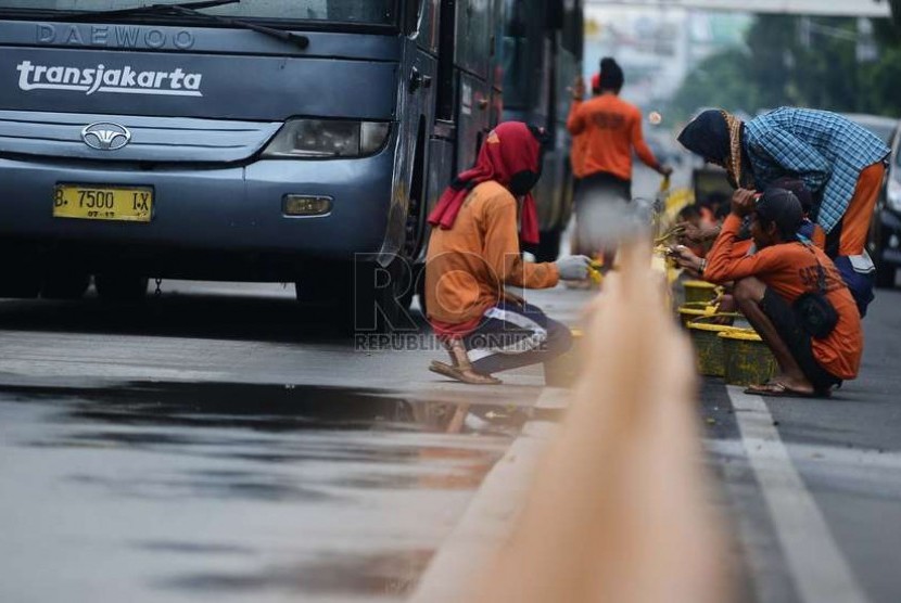 Sejumlah pekerja mengecat separator jalur busway di Jalan Raya Mampang, Jakarta Selatan, Kamis (27/11).   (Republika/Raisan Al Farisi)