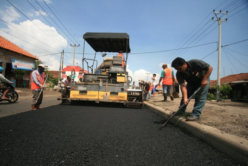 Sejumlah pekerja menggunakan alat berat melakukan pelapisan aspal di jalur pantura Lohbener, Indramayu, Jawa Barat, 