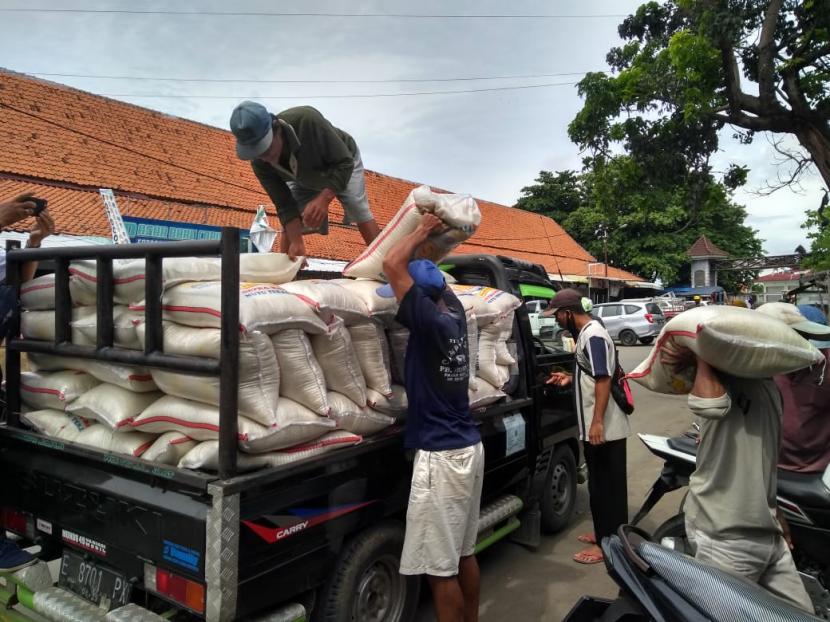 Sejumlah pekerja menurunkan beras dari mobil pengangkut ke kios beras di Pasar Baru Indramayu. 