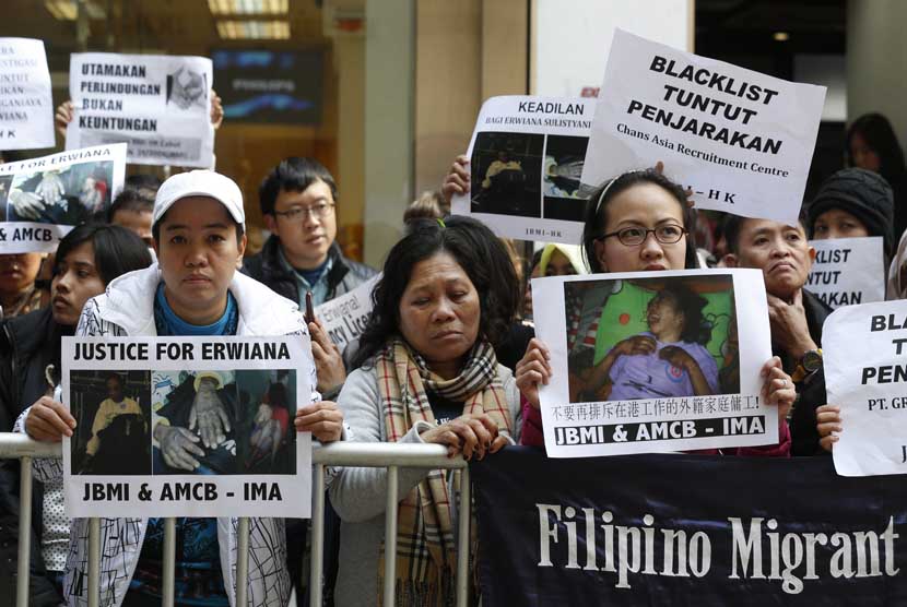   Sejumlah pekerja migran membawa foto pekerja asal Indonesia Erwiana Sulistyaningsih, saat berunjuk rasa di luar gedung Konsulat Indonesia di Hong Kong, Kamis (16/1).  (AP/Kin Cheung)