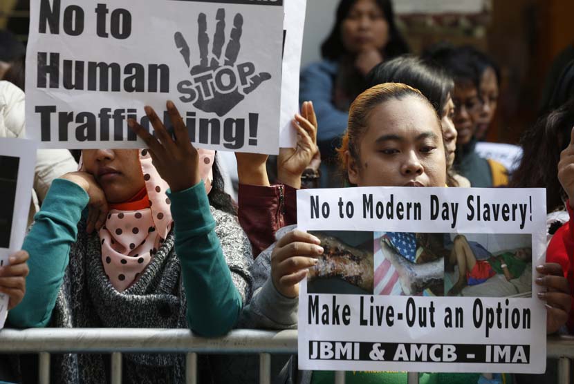   Sejumlah pekerja migran membawa foto pekerja asal Indonesia Erwiana Sulistyaningsih, saat berunjuk rasa di luar gedung Konsulat Indonesia di Hong Kong, Kamis (16/1).  (AP/Kin Cheung)