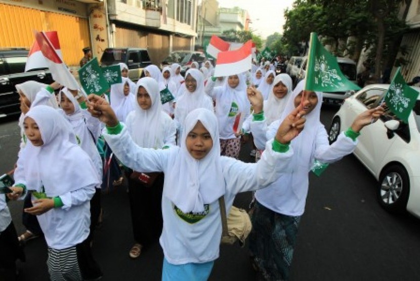 Sejumlah pelajar melambaikan bendera NU saat mengikuti jalan santai di Surabaya, Jawa Timur, Ahad  (18/10).