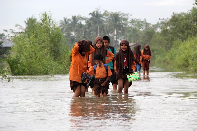 Sejumlah pelajar melintasi banjir rob di Kecamatan Sinaboi Rokan Hilir, Riau. Sejumlah daerah di Provinsi Riau sudah mencabut status siaga darurat banjir.