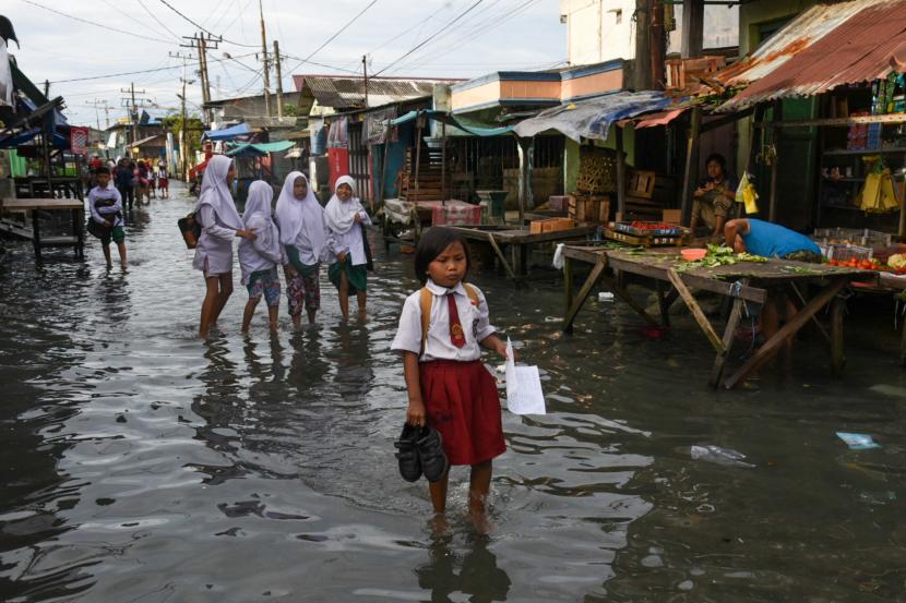 Sejumlah pelajar melintasi genangan air Kota Medan, Sumatra Utara. BMKG mengingatkan masyarakat agar waspada terhadap potensi terjadinya bencana hidrometeorologi, seperti banjir dan longsor.