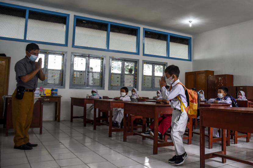 Sejumlah pelajar memberi salam kepada guru usai mengikuti pembelajaran tatap muka (PTM) 100 persen di SDN 065 Cihampelas, Jalan Cihampelas, Kota Bandung, Senin (10/1).