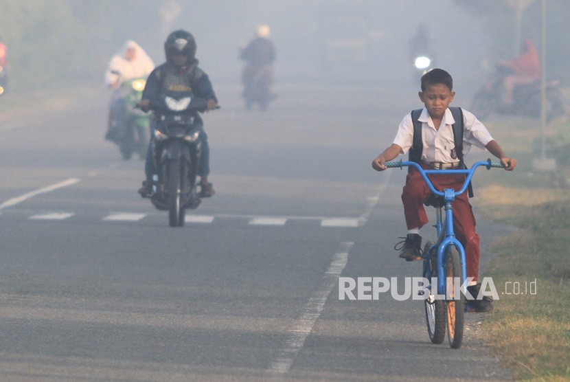 Sejumlah pelajar menembus kabut asap saat menuju ke sekolah mereka di kawasan jalan Desa Suak Timah, Samatiga, Aceh Barat, Aceh, Selasa (30/7/2019).