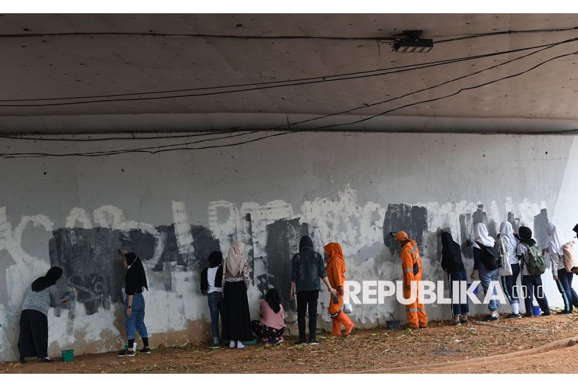 Sejumlah pelajar mengecat tembok yang menjadi sasaran vandalisme saat kericuhan terjadi dalam unjuk rasa di kawasan Senayan, Jakarta, Jumat (4/10/2019).