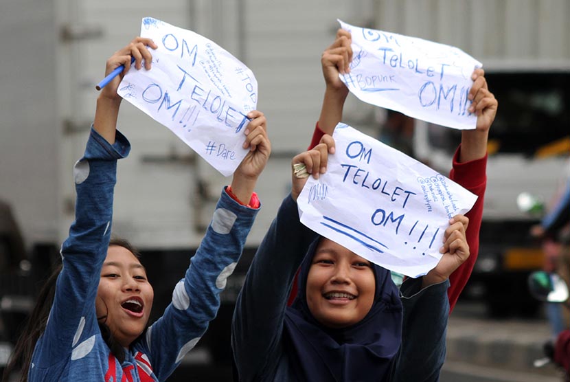 Sejumlah pelajar sekolah menuliskan pesan Om Telolet Om agar pengemudi bus membunyikan klakson di Jalan Sudirman, Bekasi, Jawa Barat, Rabu (21/12). 
