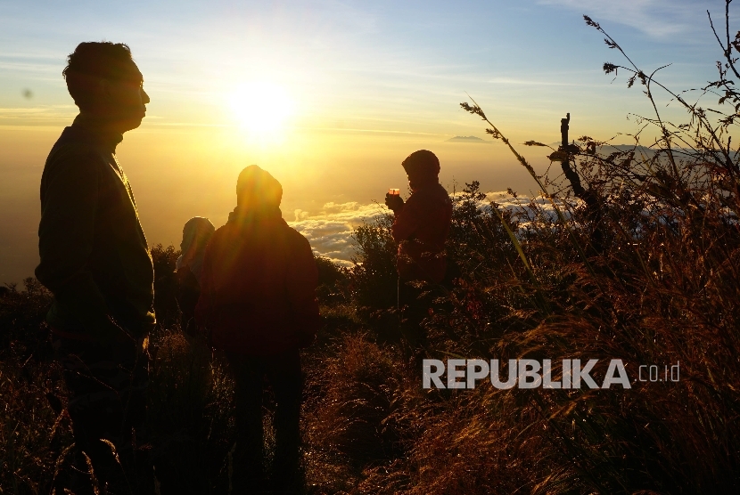 Sejumlah pendaki menikmati matahari terbit di Sendang Drajat kawasan Puncak Gunung Lawu, Perbatasan Jawa Tengah dan Jawa Timur, Jumat (19/8).