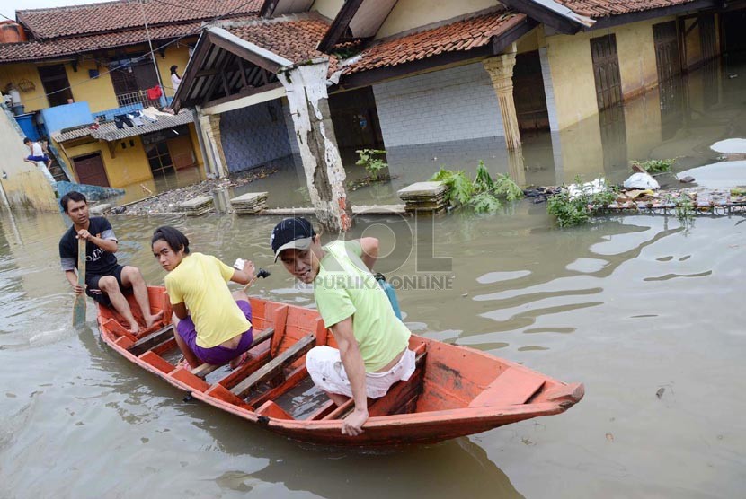 Sejumlah penduduk melintasi Jl Cieunteung, Kecamatan Baleendah, Kabupaten Bandung, yang sudah terendam Banjir, Ahad (15/12).  (Republika/Edi Yusuf)