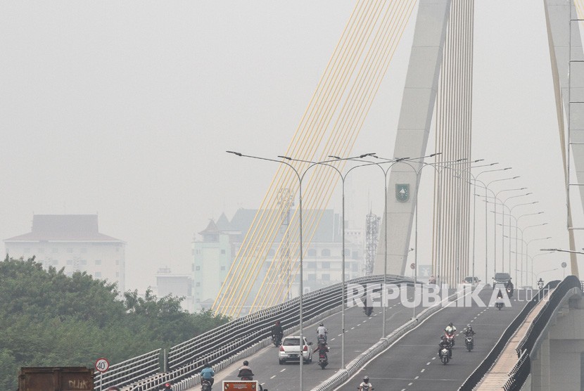 Sejumlah pengendara kendaraan bermotor melintas di atas jembatan Siak IV yang diselimuti kabut asap dampak kebakaran hutan dan lahan, di Pekanbaru, Riau, Selasa (6/8/2019). 