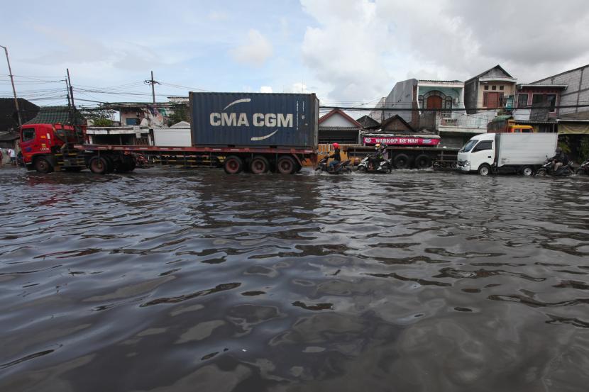 Sejumlah pengendara kendaraan bermotor melintasi banjir rob di Jalan Kalianak, Surabaya, Jawa Timur, Kamis (19/5/2022). Pasang air laut yang tinggi menyebabkan jalan tersebut tergenang banjir rob dan mengakibatkan kemacetan panjang. 