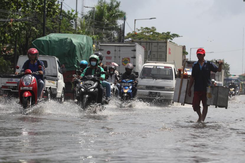 Sejumlah pengendara kendaraan bermotor melintasi banjir di Jalan Kalianak, Surabaya, Jawa Timur. Pemkot Surabaya fokus tangani kawasan perkampungan rawan banjir.