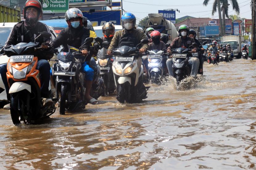 Sejumlah pengendara kendaraan menerobos genangan banjir di Jalan Raya Sawangan, Perempatan Mampang, Depok, Jawa Barat, Rabu (18/5/2022). Hujan deras yang mengguyur pada Selasa (17/5) malam hingga pagi hari membuat air sungai di sekitar lokasi meluap serta diperparah buruknya sistem drainase menyebabkan banjir dengan ketinggian sekitar 50 cm. 