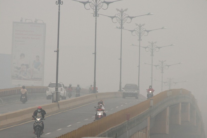 Sejumlah pengendara melintas di jalan yang dipenenuhi kabut asap kebakaran hutan dan lahan di Pekanbaru, Riau, Rabu (30/9). 