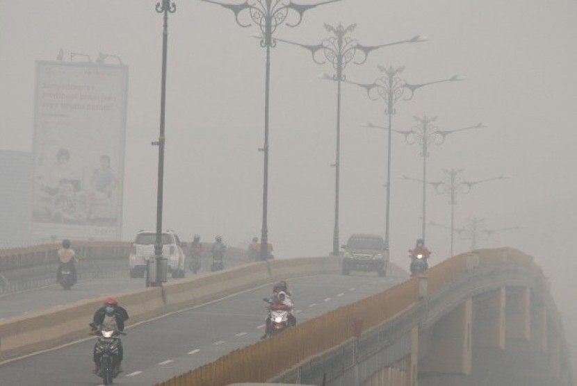 Sejumlah pengendara melintas di jalan yang dipenenuhi kabut asap kebakaran hutan dan lahan di Pekanbaru, Riau