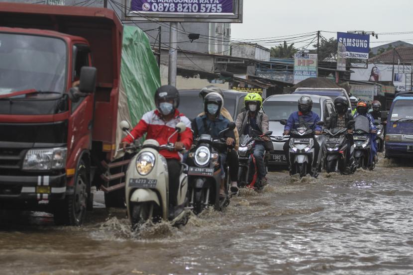 Sejumlah pengendara melintasi banjir di Kawasan Perempatan Mampang, Depok, Jawa Barat, Jumat (19/2/2021). Hujan deras yang mengguyur kawasan membuat aliran kali meluap ditambah sistem drainase yang buruk menyebabkan banjir hingga ketinggian 50 cm. 