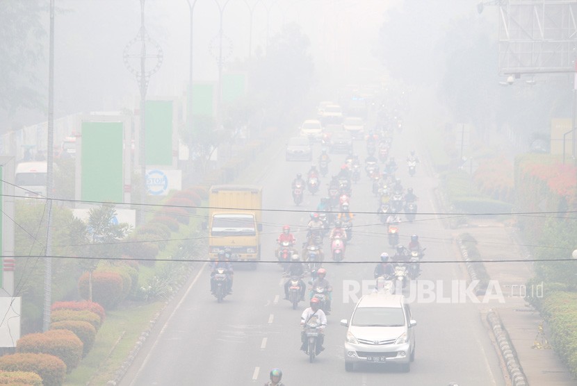 Sejumlah pengendara melintasi jalan yang diselimuti kabut asap di Pontianak, Kalimantan Barat, Senin (16/9/2019).
