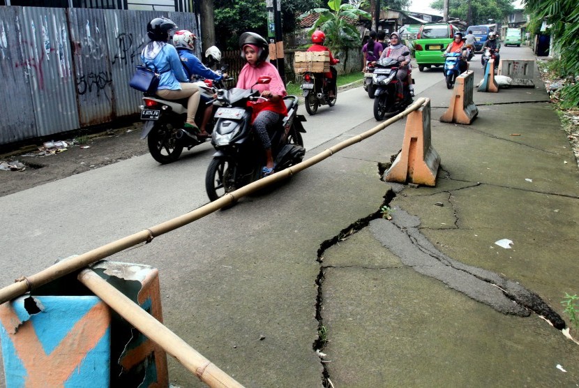 Sejumlah pengendara melintasi jalan yang longsor di Jalan Raya Cilebut, Sukaraja, Kabupaten Bogor, Jawa Barat, Jum'at (11/3).