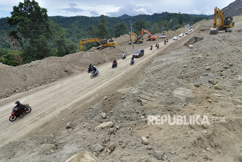 Sejumlah pengendara melintasi lokasi proyek pembangunan dan peningkatan infastruktur pada jalur jalan nasional Trans Sulawesi yang masuk ke dalam Proyek Strategis Nasional (PSN) di Kawasan Pegunungan Kebun Kopi, Sulawesi Tengah, Senin (14/5).