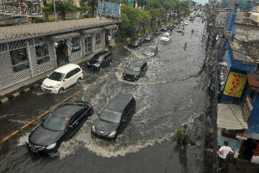 Sejumlah pengendara menerobos genangan air di Jalan Gunung Sahari, Jakarta, Ahad (18/11).