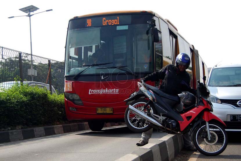 Sejumlah pengendara mengangkut motornya keluar dari jalur busway saat Polisi menggelar razia di jalan MT. Haryono, Jakarta Timur, Selasa (24/6).