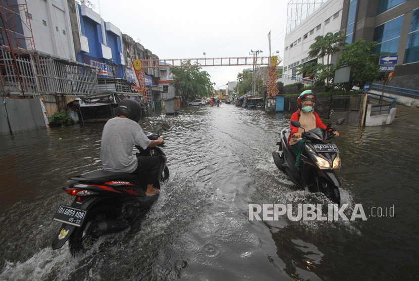 Sejumlah pengendara menorobos genangan air saat banjir melanda kawasan Jalan Brigjen Katamso, Banjarmasin, Kalimantan Selatan, Selasa (31/12/2019).