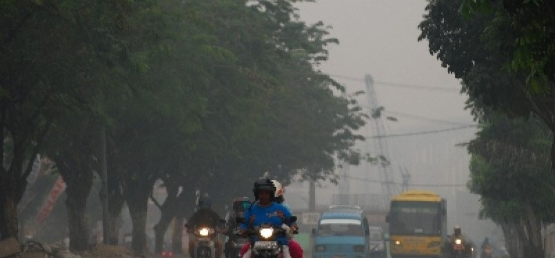 Sejumlah pengendara menyalakan lampu ketika melintas di tengah kabut asap di Pekanbaru, Riau, Ahad (10/7). 