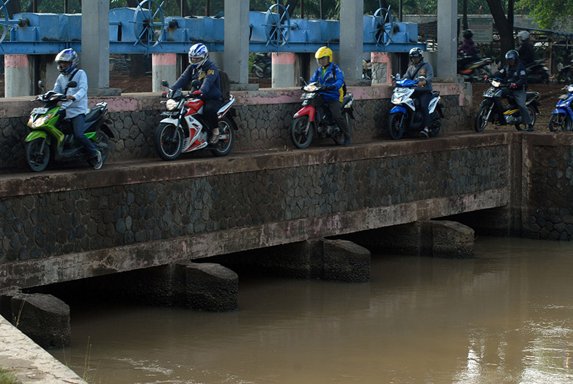 Sejumlah pengendara motor melintas di jalan setapak pintu air, Karawaci, Tangerang, Banten, Kamis (19/11).
