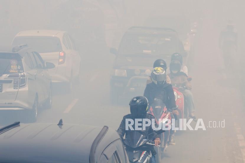 Sejumlah pengendara motor melintas di jalan yang diselimuti kabut asap kebakaran lahan di Kecamatan Liang Anggang, Banjarbaru, Kalimantan Selatan.