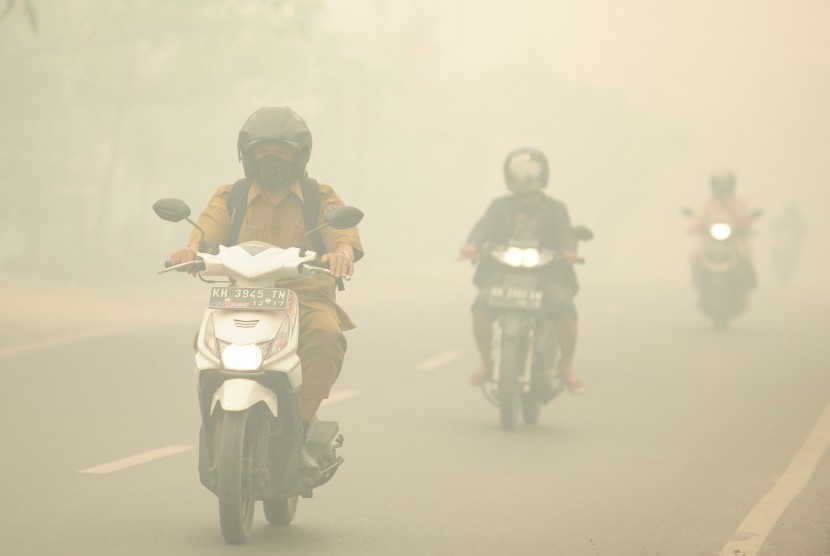 Sejumlah pengendara motor melintasi jalan yang diselimuti kabut asap pekat di Palangkaraya, Kalimantan Tengah, Selasa (27/10). 