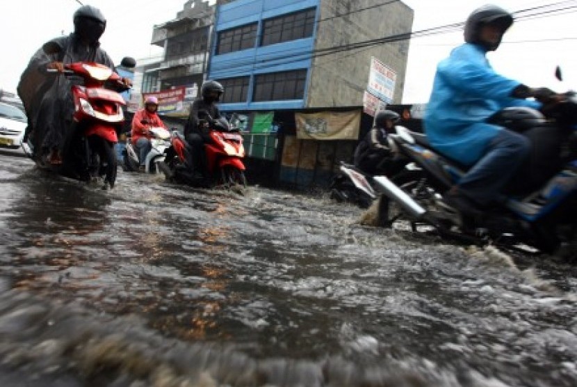 Sejumlah pengendara motor mencoba menerobos genangan air di Jalan Dewi Sartika, Ciputat, Tangerang Selatan, Banten, Sabtu (7/11).