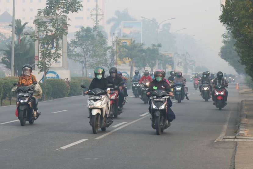 Sejumlah pengendara motor mengenakan masker saat melintasi jembatan yang diselimuti kabut asap di Pontianak, Kalbar, Jumat (24/8).